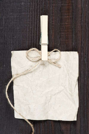Empty crumpled sheet of paper, clothespin and bow on the dark wooden tableの写真素材