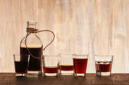 Glass bottle and shots on the wooden backgroundの写真素材