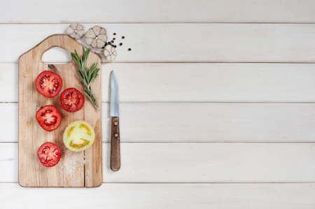 Ripe tomatoes, rosemary, garlic and pepper on the white wooden tableの写真素材