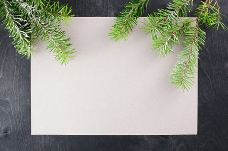 Blank sheet of paper and pine branches on the dark wooden table