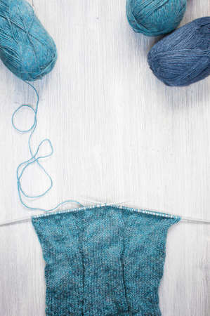 Knitted blue scarf and skeins of wool on the wooden tableの写真素材