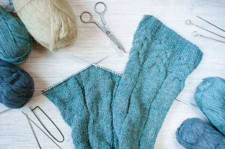 Knitted blue cloth and skeins of wool on the wooden tableの写真素材