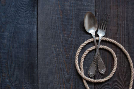 Vintage cutlery and rope on the old dark wooden tableの写真素材