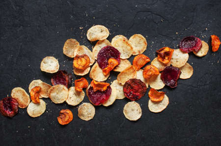 Homemade vegetable chips on the black tableの写真素材