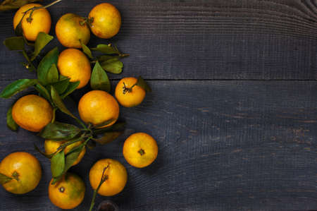 Yellow mandarins on the dark wooden tableの写真素材