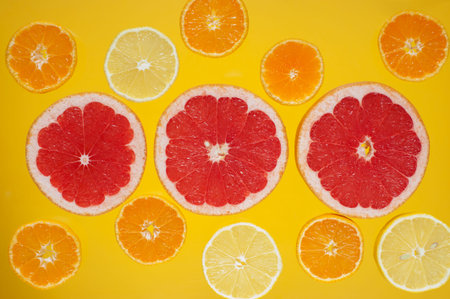 Slices of citrus fruits on the bright yellow background