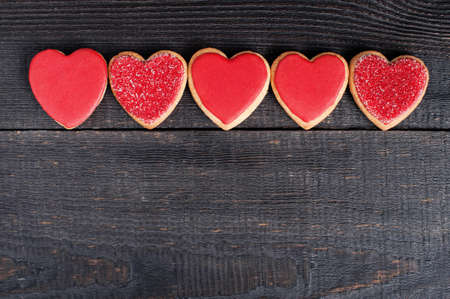 Red cookies with red icing on the old wooden tableの写真素材