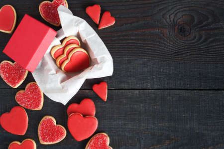 Red cookies with red icing and box on the old brown wooden tableの写真素材