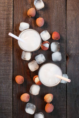 Two glasses of cold lychee juice on the old wooden table の写真素材