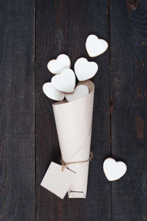 Packaged white cookies-hearts with icing on the vintage wooden tableの写真素材