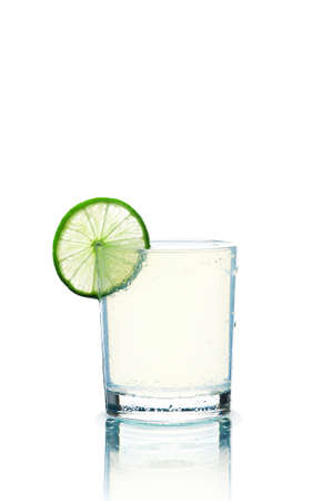 Glass of transparent beverage and lime slice on the white backgroundの写真素材