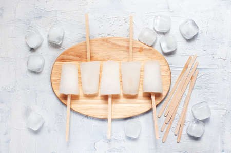 Lollies and ice cubes on the board, on the white tableの写真素材