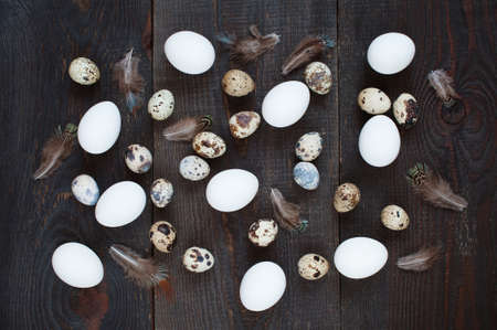 Chicken and quail eggs scattered on the brown wooden tableの写真素材