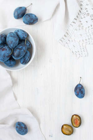 Wooden background with plums and white towelの写真素材