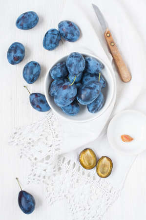 Wooden white table with plums and white towelの写真素材