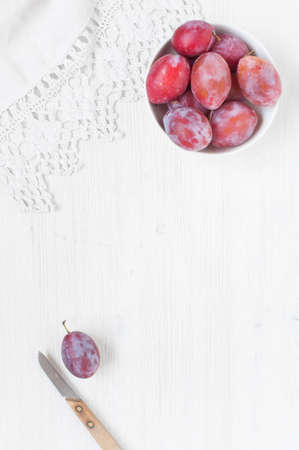 Wooden white table with plums and white towelの写真素材