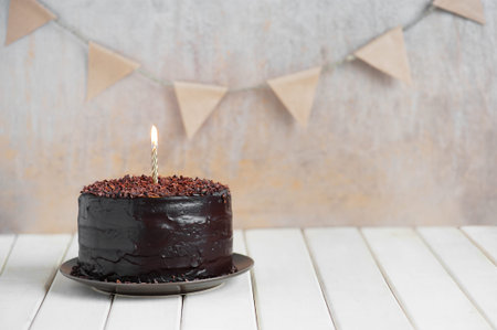 Chocolate birthday cake with burning candle and deroration
