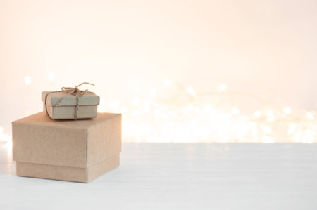 Gift boxes on the white wooden table, against the background of the garland