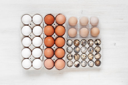 Some types of eggs in the packages on the white wooden table