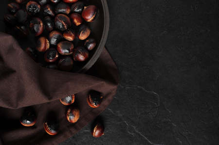 Black backkground with roasted chestnuts on the panの写真素材