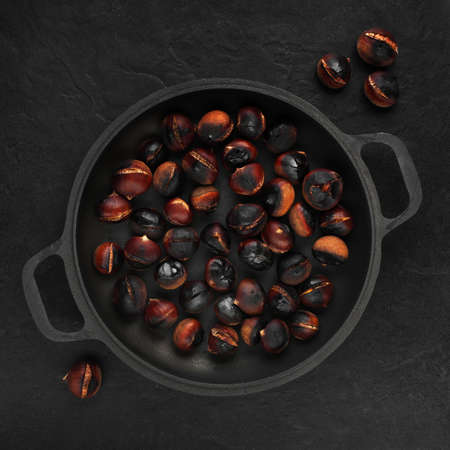 Pan with roasted chestnuts on the black stone tableの写真素材