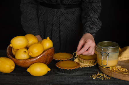 Woman cook tartlets with lemon curd and decorates with lemon zest.の写真素材