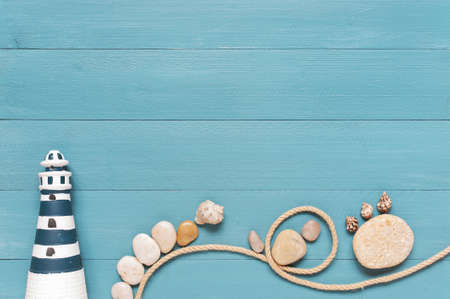 Blue wooden background decorated with lighthouse, rope, pebble and shellsの写真素材