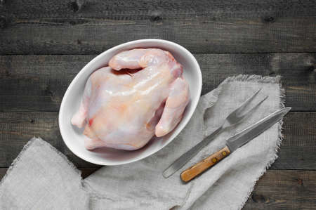 Raw chicken in the white plate on the dark wooden tableの写真素材