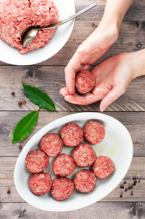 Female hands prepare meatballs on the wooden table, top viewの写真素材
