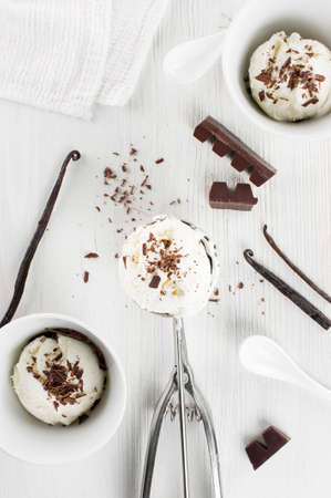 Portions of vanilla ice-cream with chocolate topping on the wooden table, top viewの写真素材