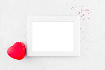 Empty wooden frame and red gift box-heart on the white textured surfaceの写真素材