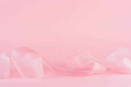 Light pink background with tender ribbon. Festive background with copy space.の写真素材