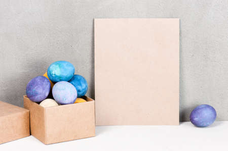 Blanc sheet of craft paper on the table decorated with colored easter eggs, copy space の写真素材