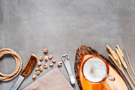 Mug of beer with foam and decoration on the gray table, copy space, top view 