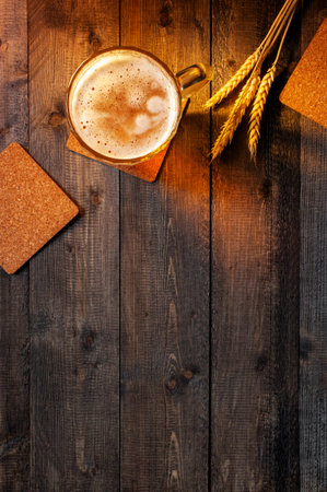 Wooden background with beer mug and wheat ears in the rays of the sunset, copy space