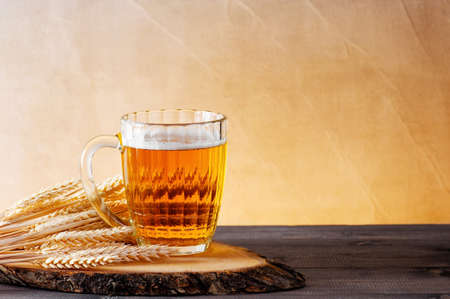 Mug of light beer and wheat ears on the wooden tabe, copy spaceの写真素材