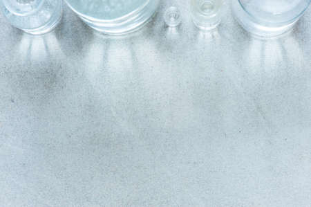 Textured gray background with glass bottles and glare of light, copy spaceの写真素材