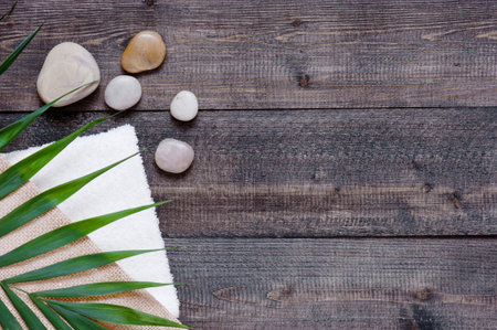 Brown wooden background with terry towel, palm leaf and stones. Copy spaceの写真素材