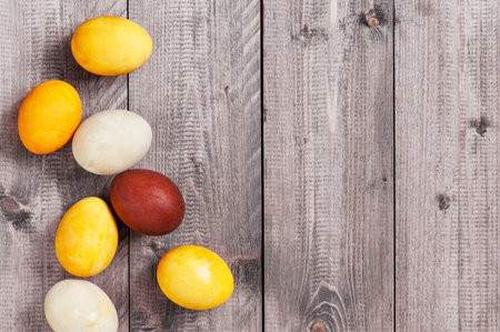 Background with Easter eggs on the gray wooden table, copy space