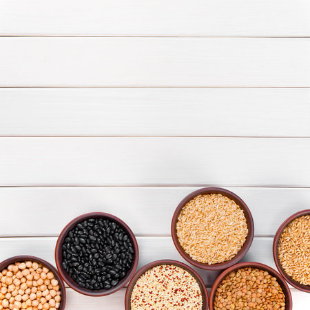 Background with healthy various cereals in the bowls on the white wooden table, copy space