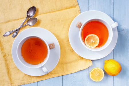 Two cups of tea with lemon on the light-blue wooden table, flat layの写真素材