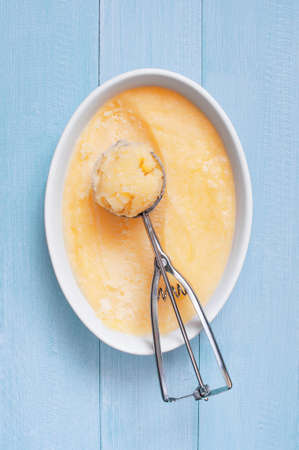 Homemade lemon sorbet in the white bowl on the blue wooden table, top viewの写真素材