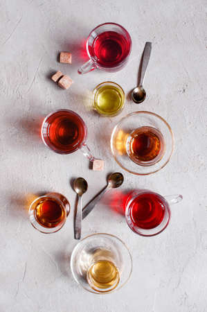 Glass cups with various types of tea on the textured grey table, top viewの写真素材