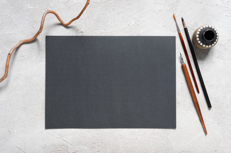 Blank sheet of black textured paper and drawing tools on the grey table, top viewの写真素材