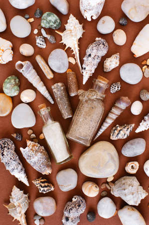 Pattern of sand in the glass bottles, sea shells and stones on the brown paper background, flat layの写真素材