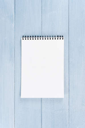 Blank sheet of opened notepad on the blue textured wooden table, copy spaceの写真素材