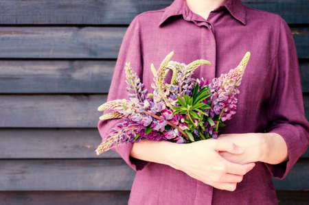 Woman holding the bouquet of colorful lupines, background with copy spaceの写真素材