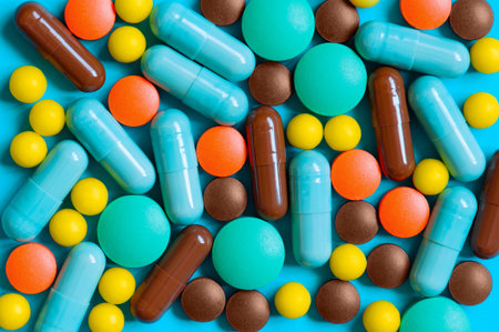 Colorful pills scattered on the blue background, top view