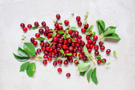 Fresh ripe cherries with leaves on the textured grey table, top viewの写真素材