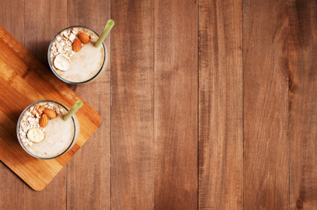 Wooden background with fresh banana smoothies, decorated with almond and banana chips, copy spaceの写真素材